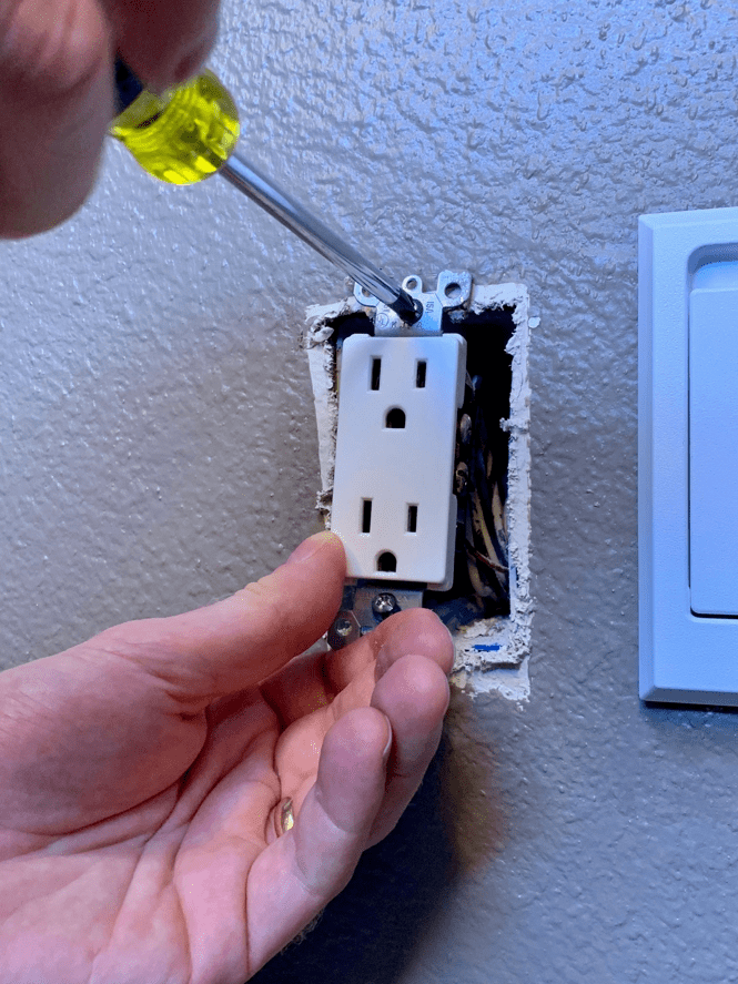 Person installing an outlet in the wall 